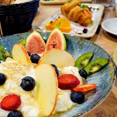 Bunt dekorierter Obstsalat mit Joghurt, Beeren, und frischen Früchten in einer Schale.